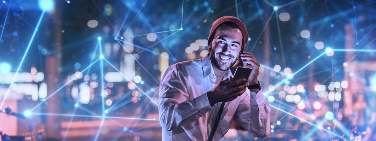 Person smiling with mobile in one hand and adjust his ear phone with other hand