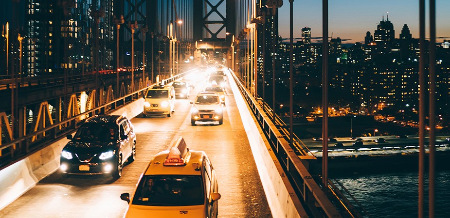 Cars driving across a suspension bridge at night.